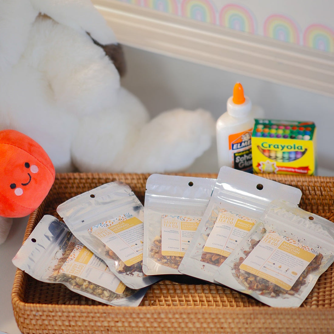 Assorted loose leaf tea packages on a tray with a plush toy and Crayola products in the background for Back to School time.