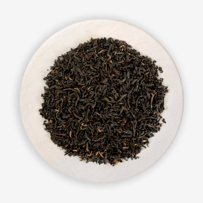 A pile of black tea leaves on a white background.