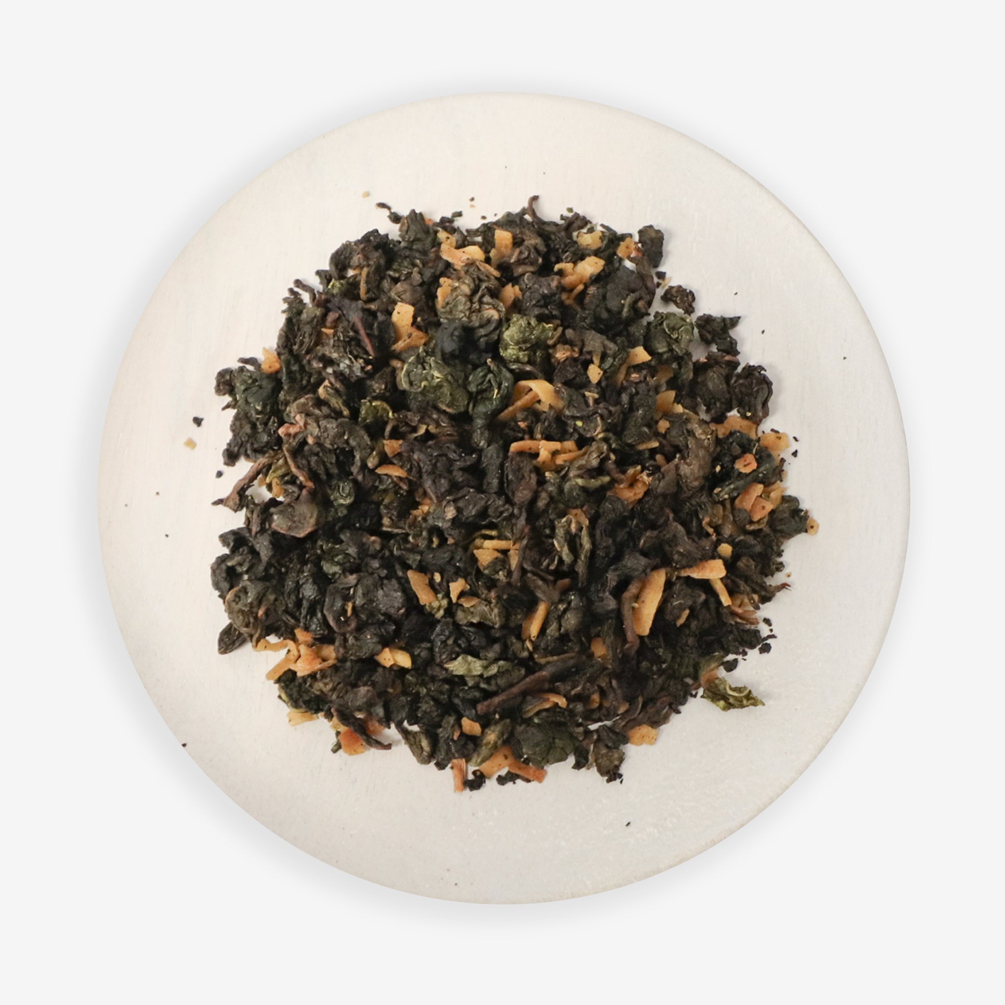 A close-up image of Coconut Oolong tea leaves with pieces of coconut visible, on a white plate against a white background.