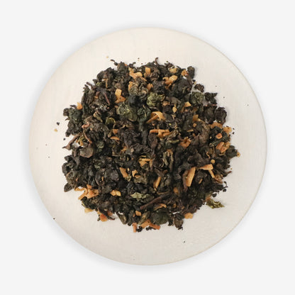 A close-up image of Coconut Oolong tea leaves with pieces of coconut visible, on a white plate against a white background.