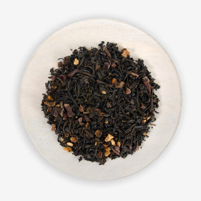 A close-up image of a tea blend containing black tea leaves, cacao nibs, and grapefruit peel, indicative of the product &