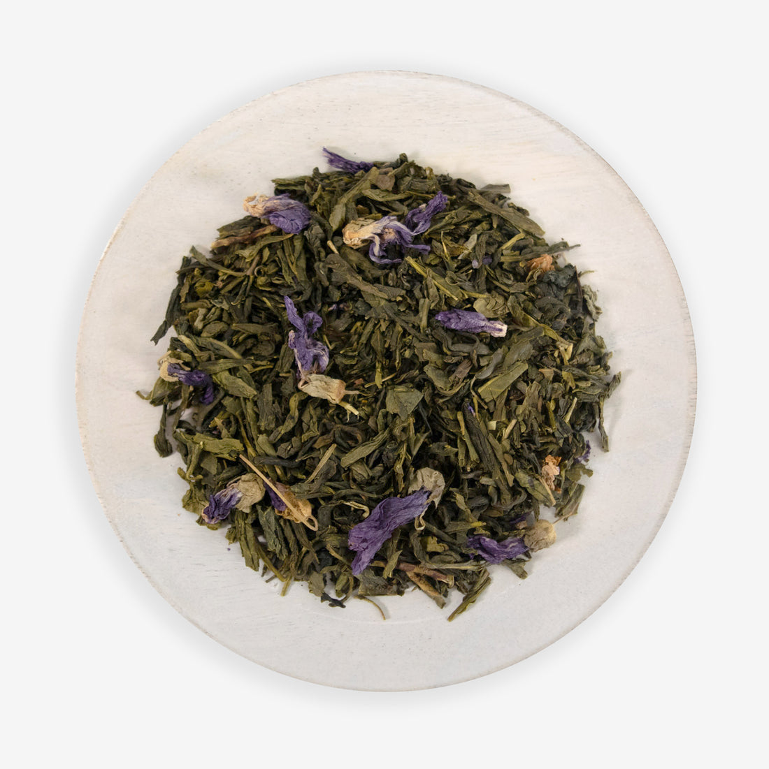 A plate with loose leaf tea that includes green tea buds and purple dragonfruit pieces, along with candied flower petals.
