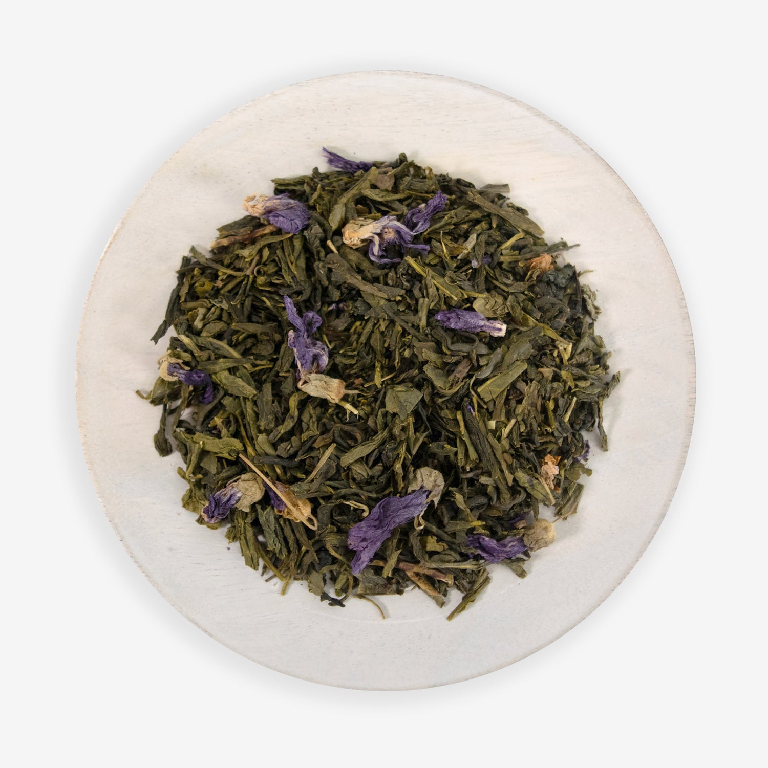 A plate with loose leaf tea that includes green tea buds and purple dragonfruit pieces, along with candied flower petals.