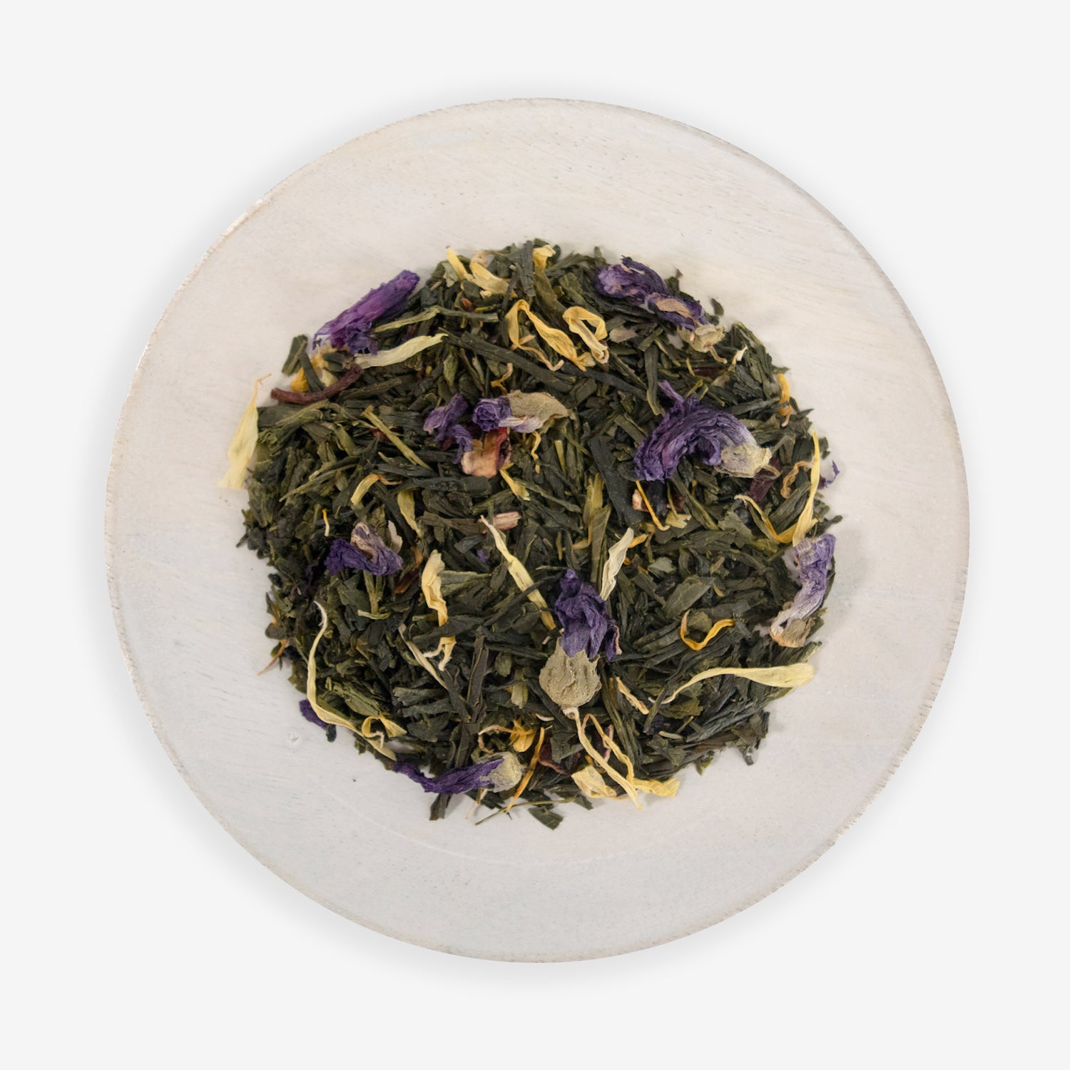A top view of a plate containing dried tea leaves and pieces of hibiscus flowers, with hints of purple and yellow, on a white background.