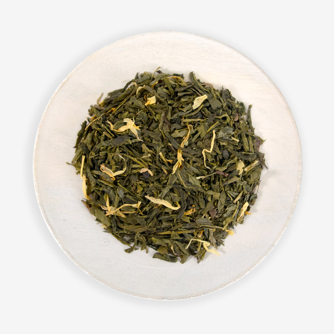 A dish containing green tea leaves with pieces of lemon and Calendula petals.