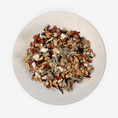 A mixture of dried fruits and herbs on a plate, likely to be used as ingredients for Pomberry Punch tea.